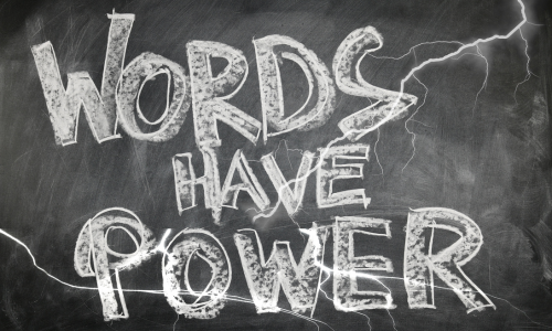 The phrase Words Have Power written in white on a chalk board with flashes of lightening around them 